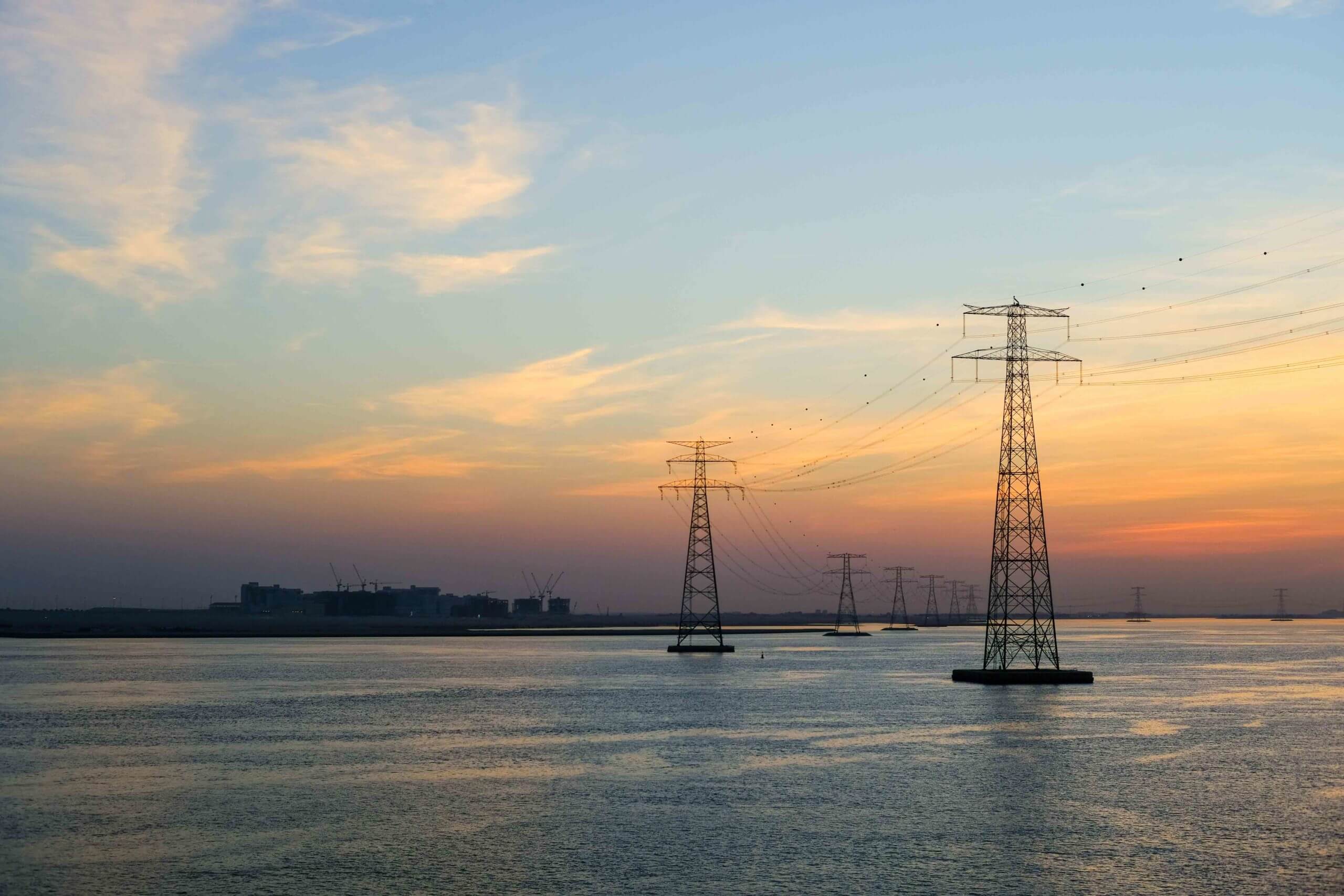 High voltage Electricty Power lines distributed through Ocean with amazing colourful clouds in background, Abu Dhabi, UAE