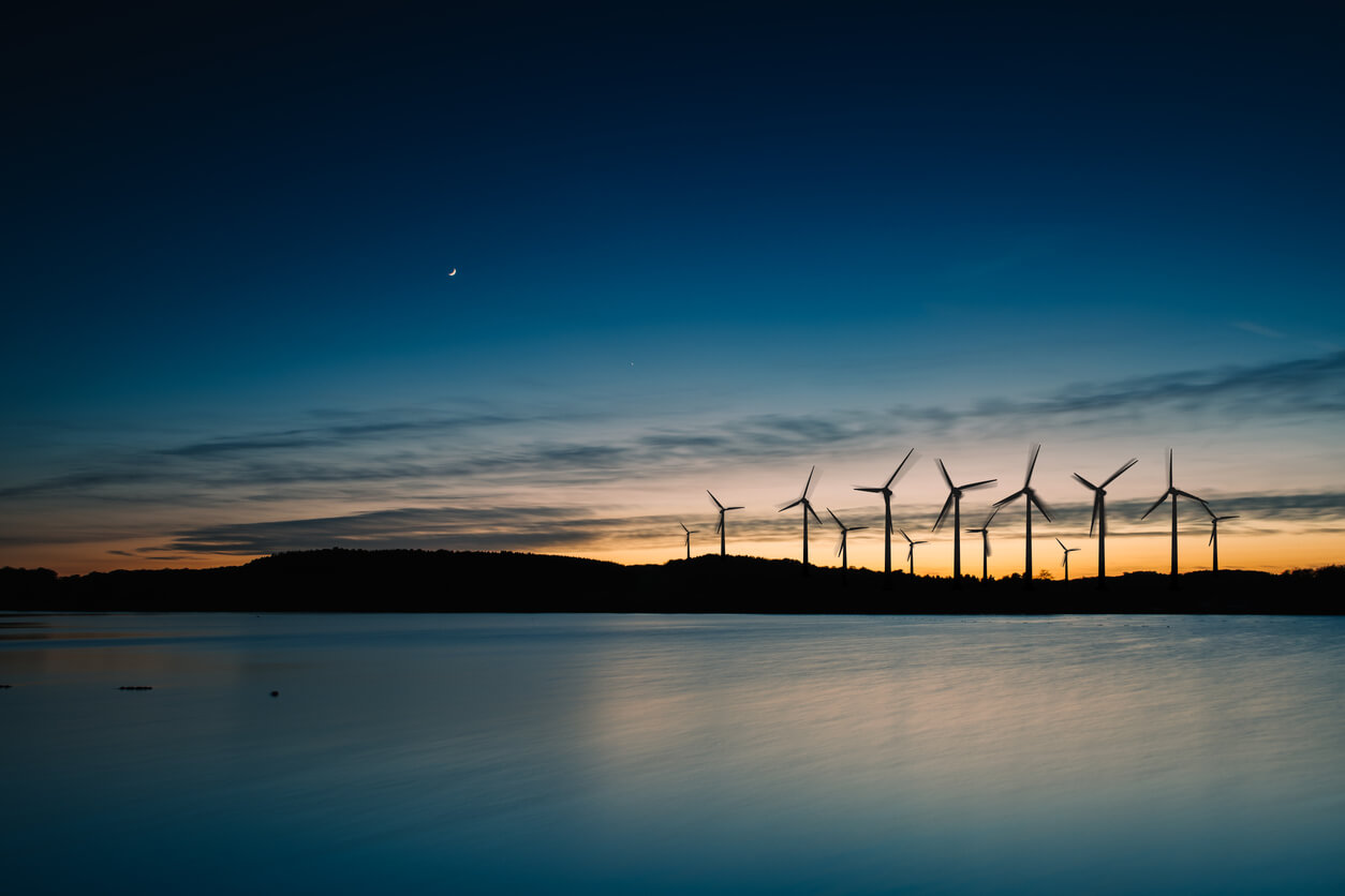 Windmills in the sunset. Wind turbines motion landscape at sunset with plane in background